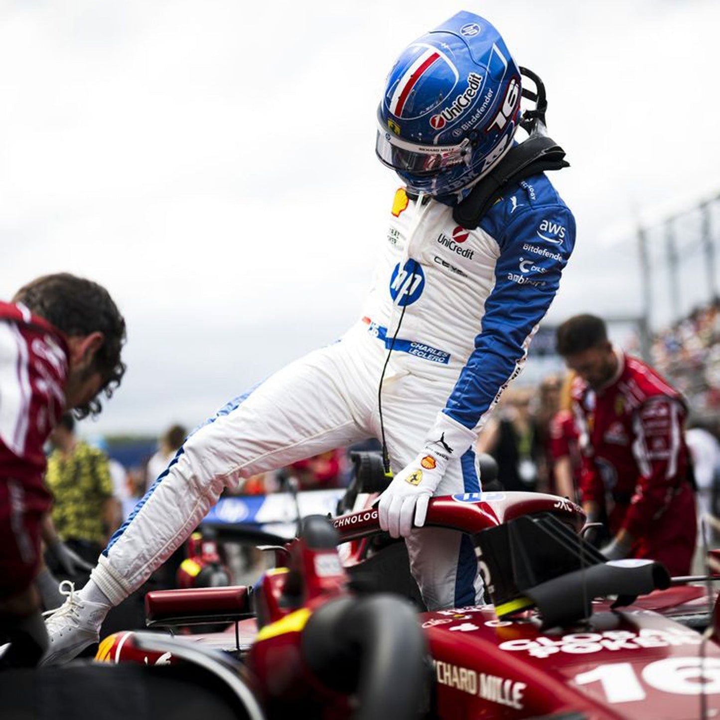 with helmet, leaning on a red Formula 1 car.