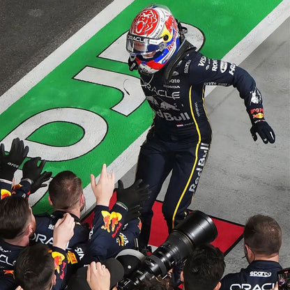 Race car driver Max Verstappen in 2025 Red Bull Las Vegas GP is celebrating on a podium with team members and branding visible - GPX WEAR