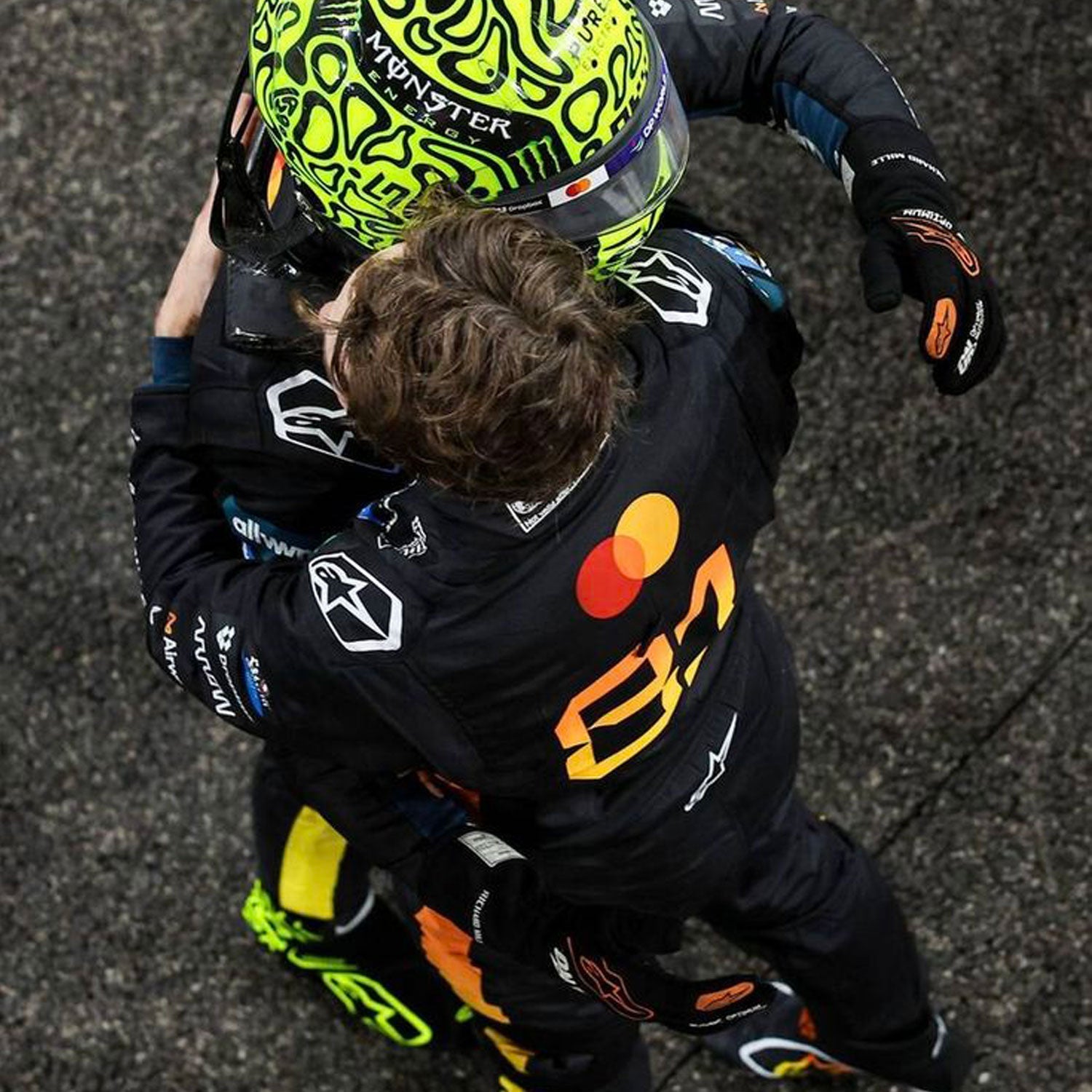 Two Formula 1 drivers embracing on a racetrack