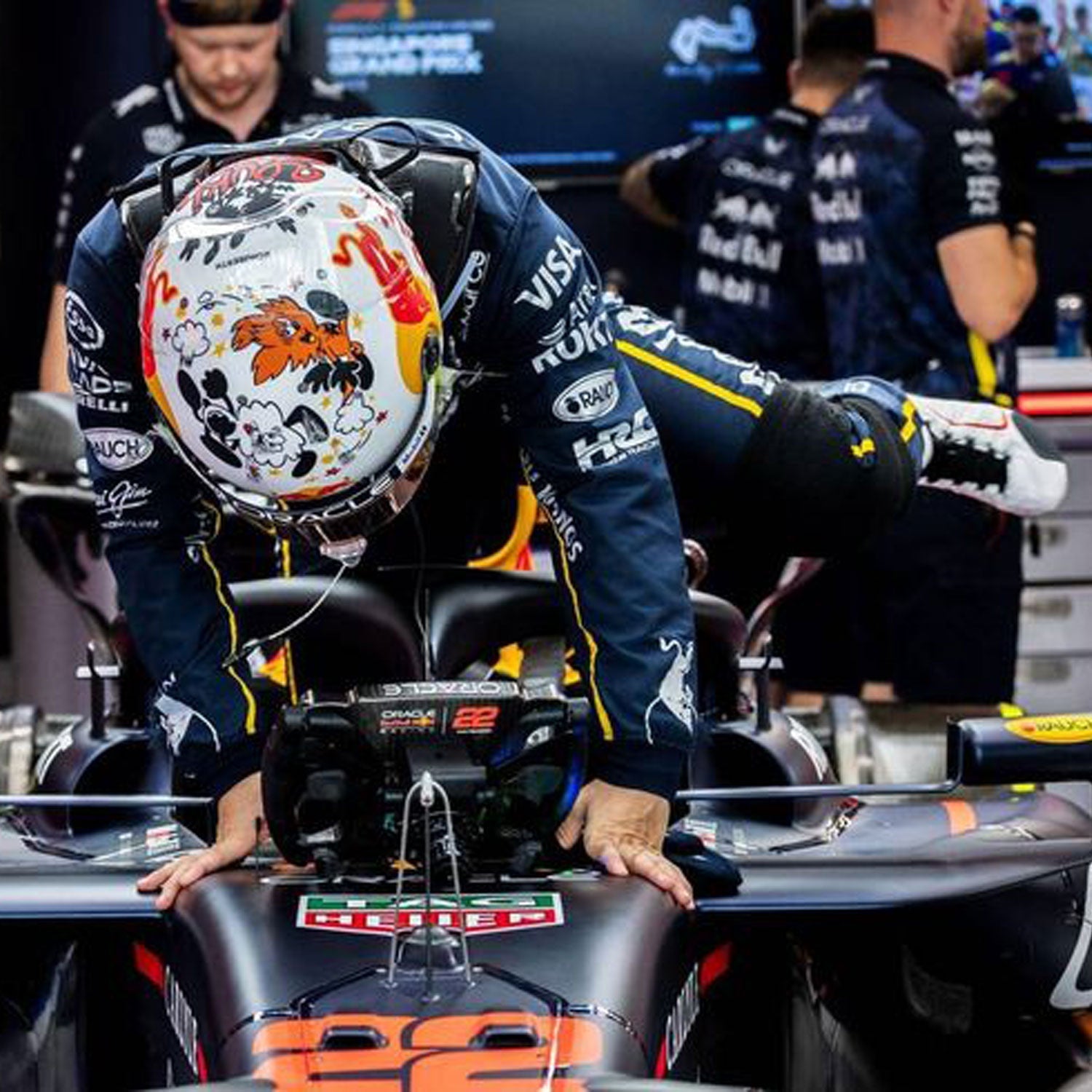 Yuki Tsunoda wearing a black 2025 Red Bull Las Vegas GP F1 racing suit and helmet leaning on a Formula 1 car with team logos - GPX WEAR