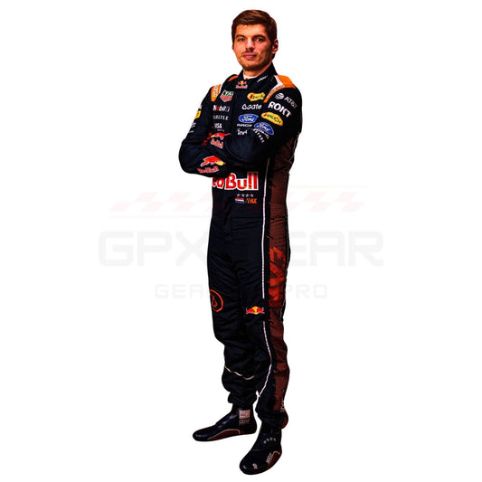 A full-body cutout of a Max Verstappen wearing a Red Bull racing suit, standing with arms crossed against a plain white background. The suit is primarily black with prominent red, orange, and white sponsor logos and graphics, including Red Bull, Ford, and Castore.