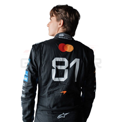 A Oscar Piastri wearing a black long-sleeve racing suit with multiple colorful sponsor logos, photographed against a plain white background.