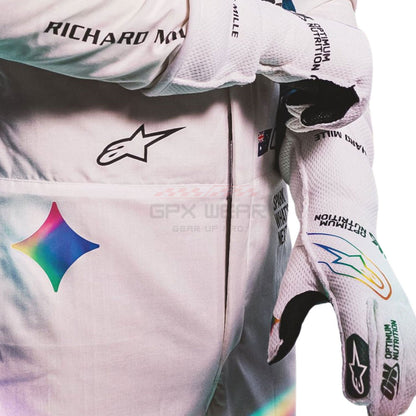 Close-up of a white Alpinestars racing suit and matching gloves with sponsor logos including Richard Norris, GPX Wear, and World Grid, featuring a holographic star logo on the chest.